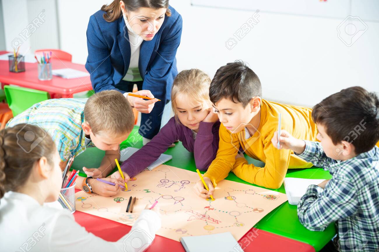 Teacher and collective of elementary age children draw together a board game - 140807919 Teacher and collective of elementary age children draw together a board game - 140807919