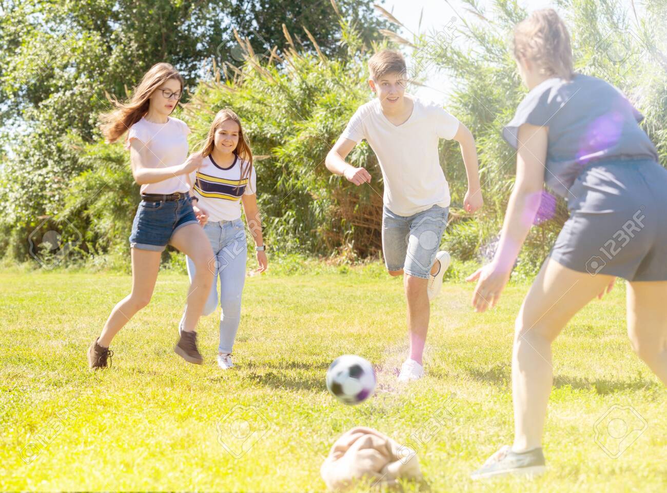 Cheerful teenagers are jogning with ball in spring park - 149849189 Cheerful teenagers are jogning with ball in spring park - 149849189