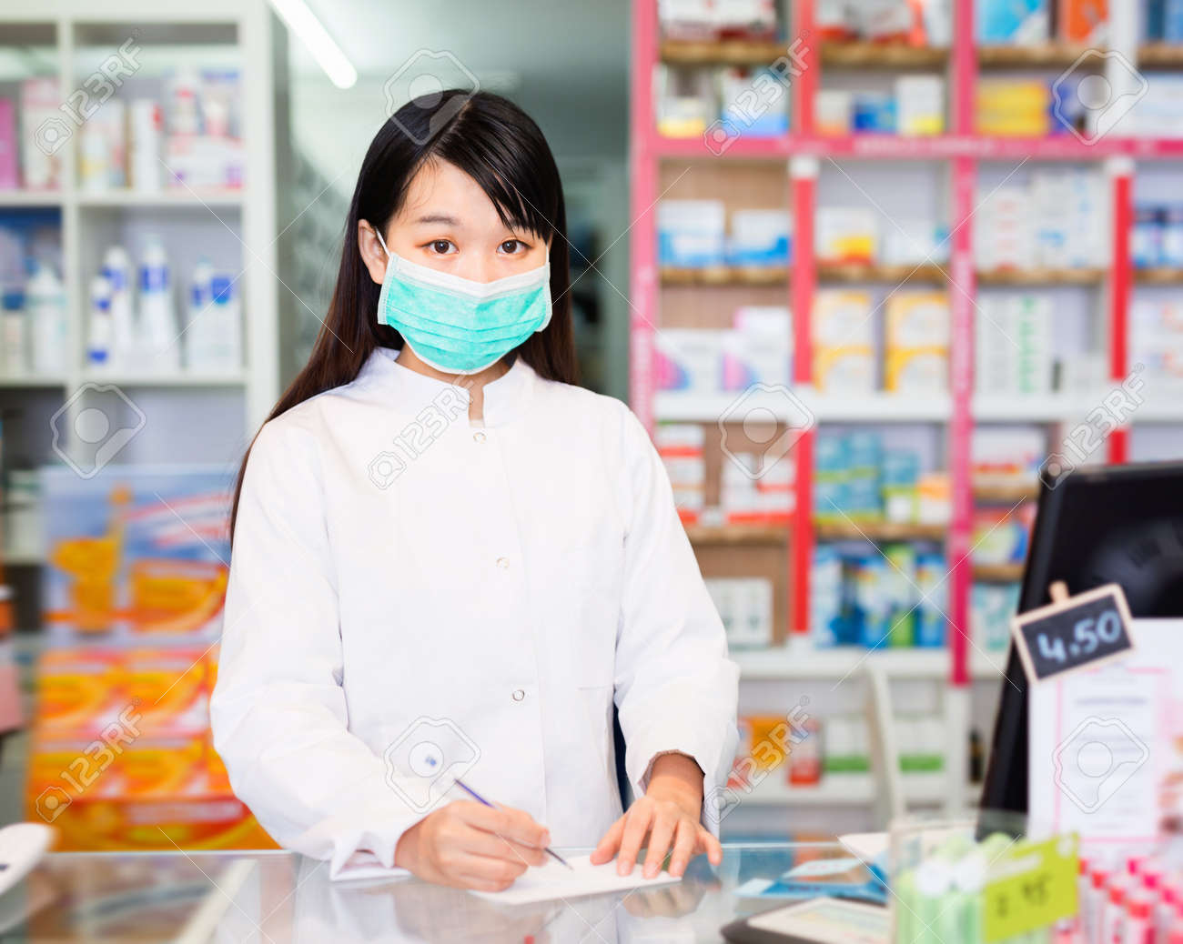 Chinese woman pharmacist keeps track of drugs in interior of pharmacy - 165484745 Chinese woman pharmacist keeps track of drugs in interior of pharmacy - 165484745