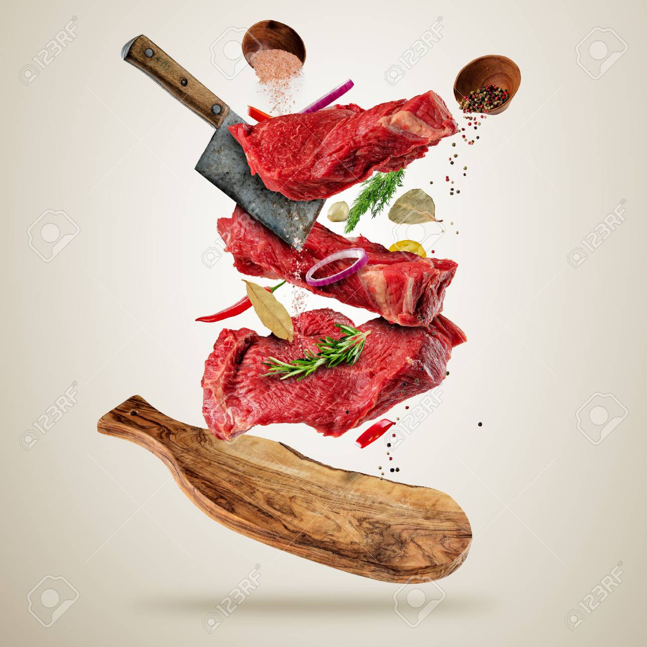 Flying pieces of raw beef steaks, with herbs, served on woodenboard. Meat chopper cuting the flesh. Concept of food preparation in low gravity mode. Separated on smooth gray background - 74520641 Flying pieces of raw beef steaks, with herbs, served on woodenboard. Meat chopper cuting the flesh. Concept of food preparation in low gravity mode. Separated on smooth gray background - 74520641