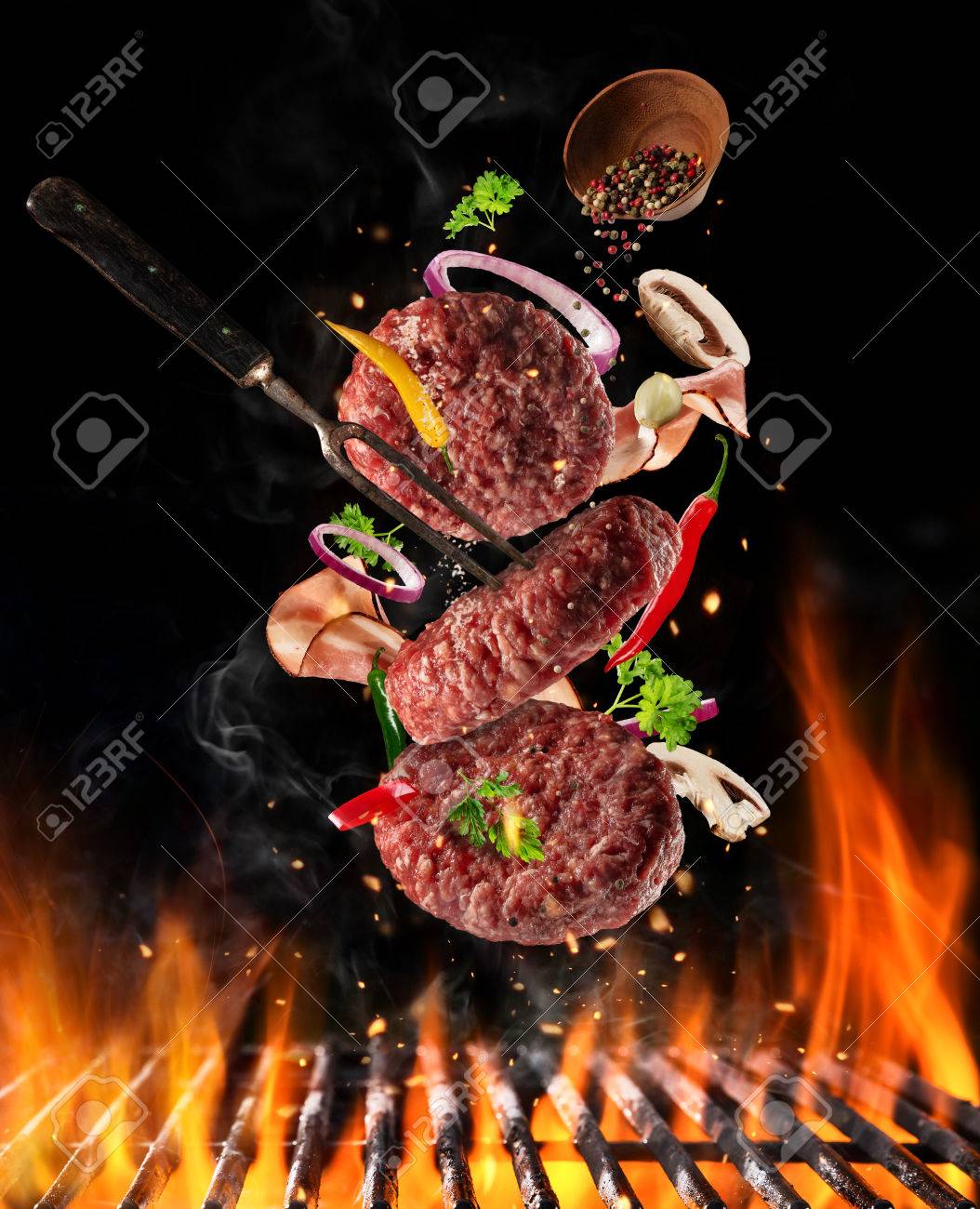 Flying raw milled beef meat, with ingredients for cooking above grill fire. Freeze motion of cooking staff. Fork holding the meat. Concept of food preparation in low gravity mode. - 76366193 Flying raw milled beef meat, with ingredients for cooking above grill fire. Freeze motion of cooking staff. Fork holding the meat. Concept of food preparation in low gravity mode. - 76366193
