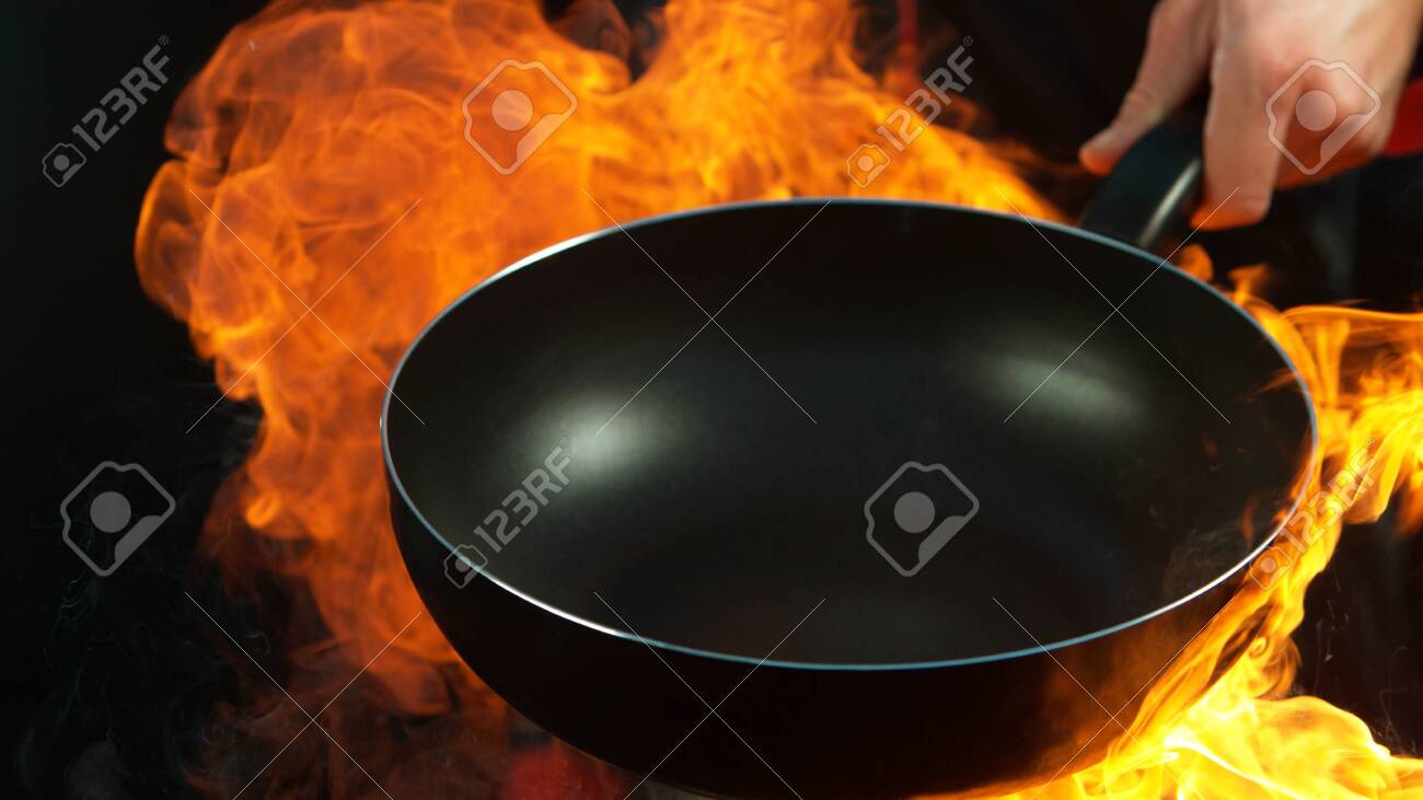 Closeup of chef holding empty wok pan with flames. Isolated on black background - 131513238 Closeup of chef holding empty wok pan with flames. Isolated on black background - 131513238