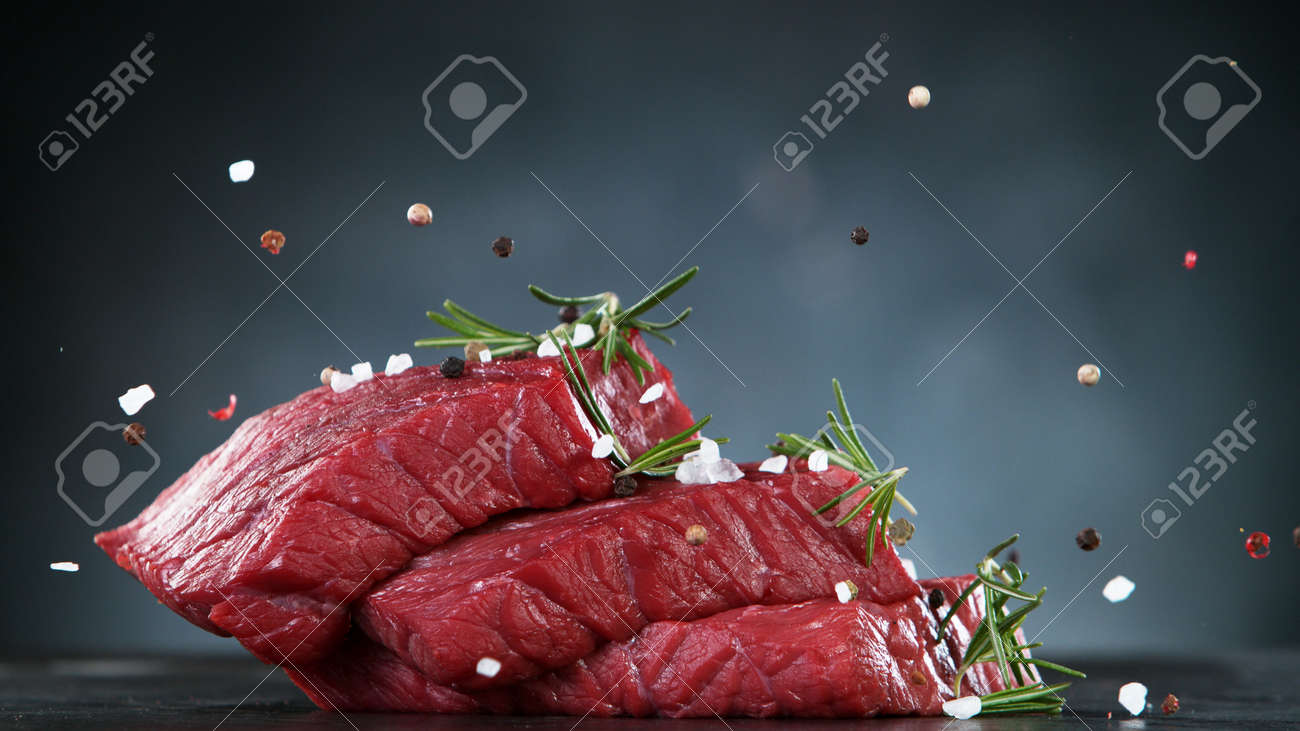 Raw beef steaks on stone table, ready to cook. Free space for text. - 168510296 Raw beef steaks on stone table, ready to cook. Free space for text. - 168510296
