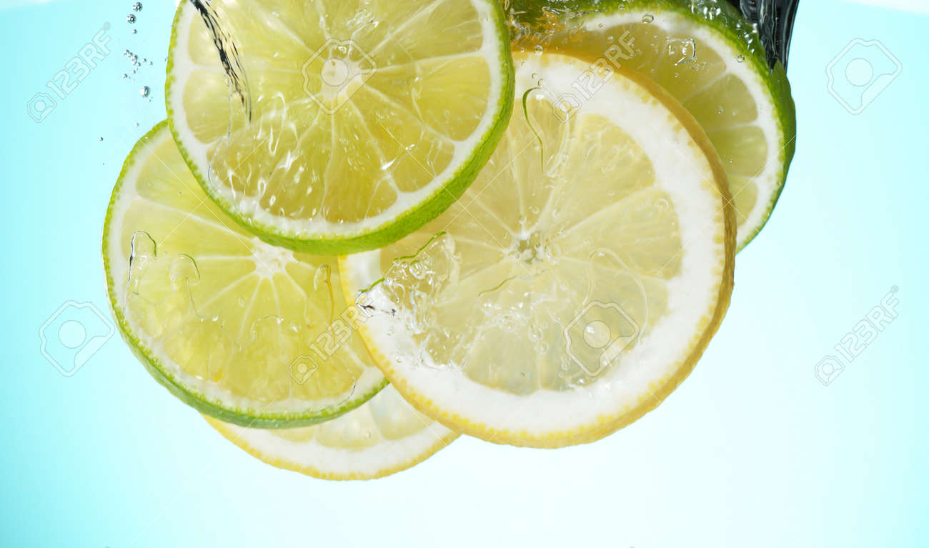 Fresh lime dropped into water with splash and ice cubes. Studio shot with clear background. - 170440652 Fresh lime dropped into water with splash and ice cubes. Studio shot with clear background. - 170440652