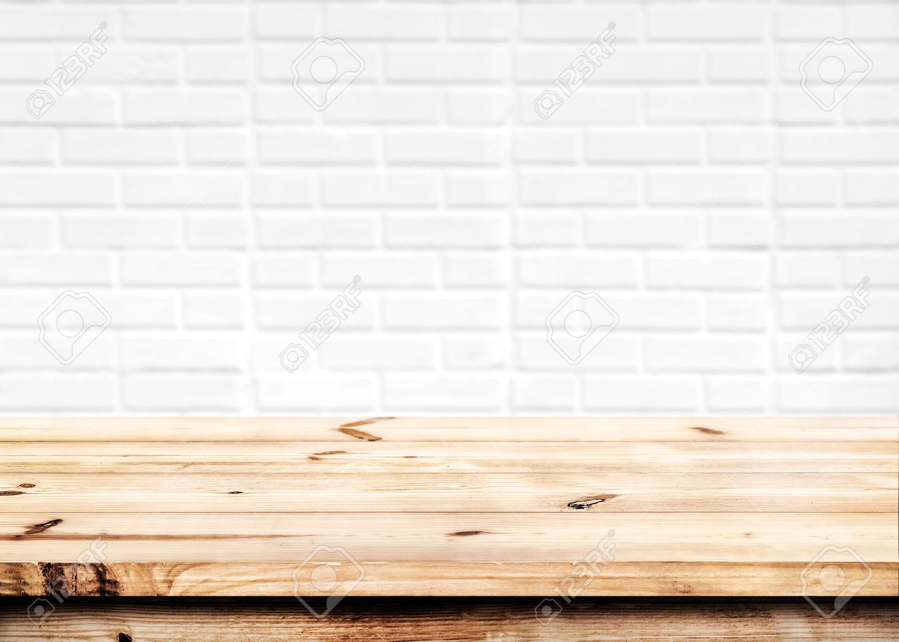 Empty wooden table for product placement or montage with focus to the table top in the foreground, with white brick wall background. - 52070148 Empty wooden table for product placement or montage with focus to the table top in the foreground, with white brick wall background. - 52070148