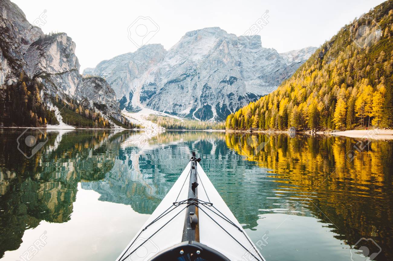 Beautiful view of kayak on a calm lake with amazing reflections of mountain peaks and trees with yellow autumn foliage in fall, Lago di Braies, Italy - 113997392 Beautiful view of kayak on a calm lake with amazing reflections of mountain peaks and trees with yellow autumn foliage in fall, Lago di Braies, Italy - 113997392