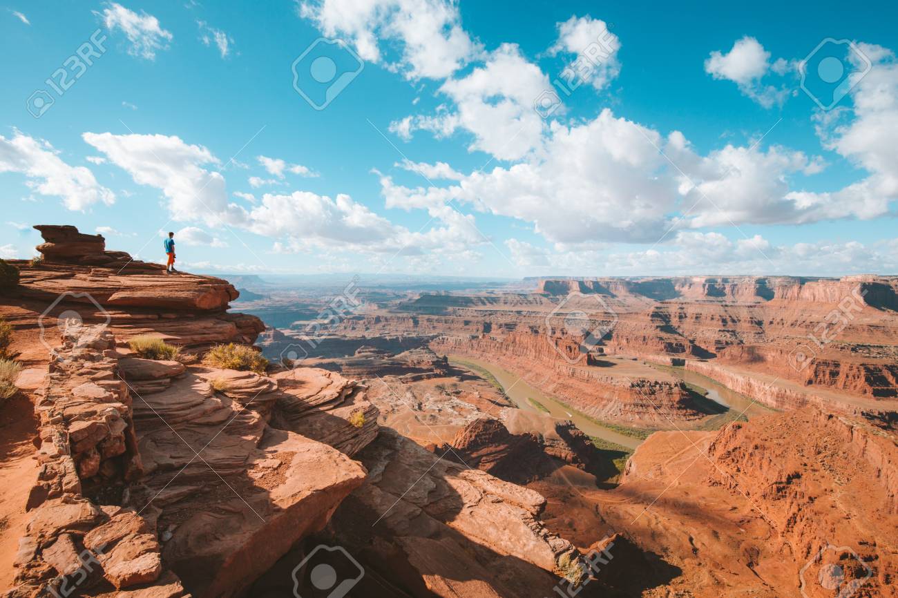 A young hiker is standing on the edge of a cliff enjoying a dramatic overlook of famous Colorado River and beautiful Canyonlands National Park in scenic Dead Horse Point State Park, Utah, USA - 121795173 A young hiker is standing on the edge of a cliff enjoying a dramatic overlook of famous Colorado River and beautiful Canyonlands National Park in scenic Dead Horse Point State Park, Utah, USA - 121795173