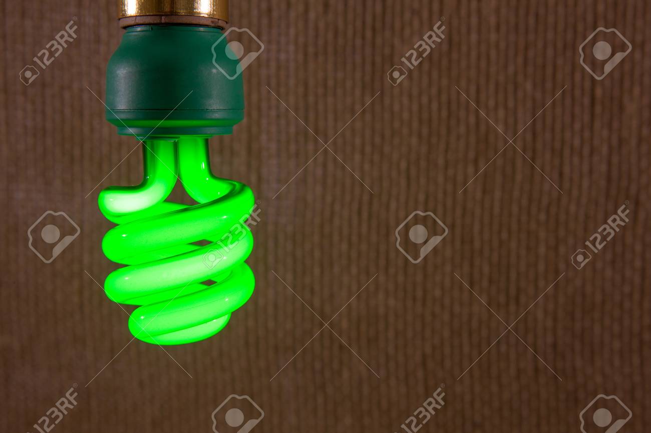1 つの緑の Cfl のクローズ アップ コンパクト蛍光灯電球黄麻布の織り目加工の背景の前で の写真素材 画像素材 Image