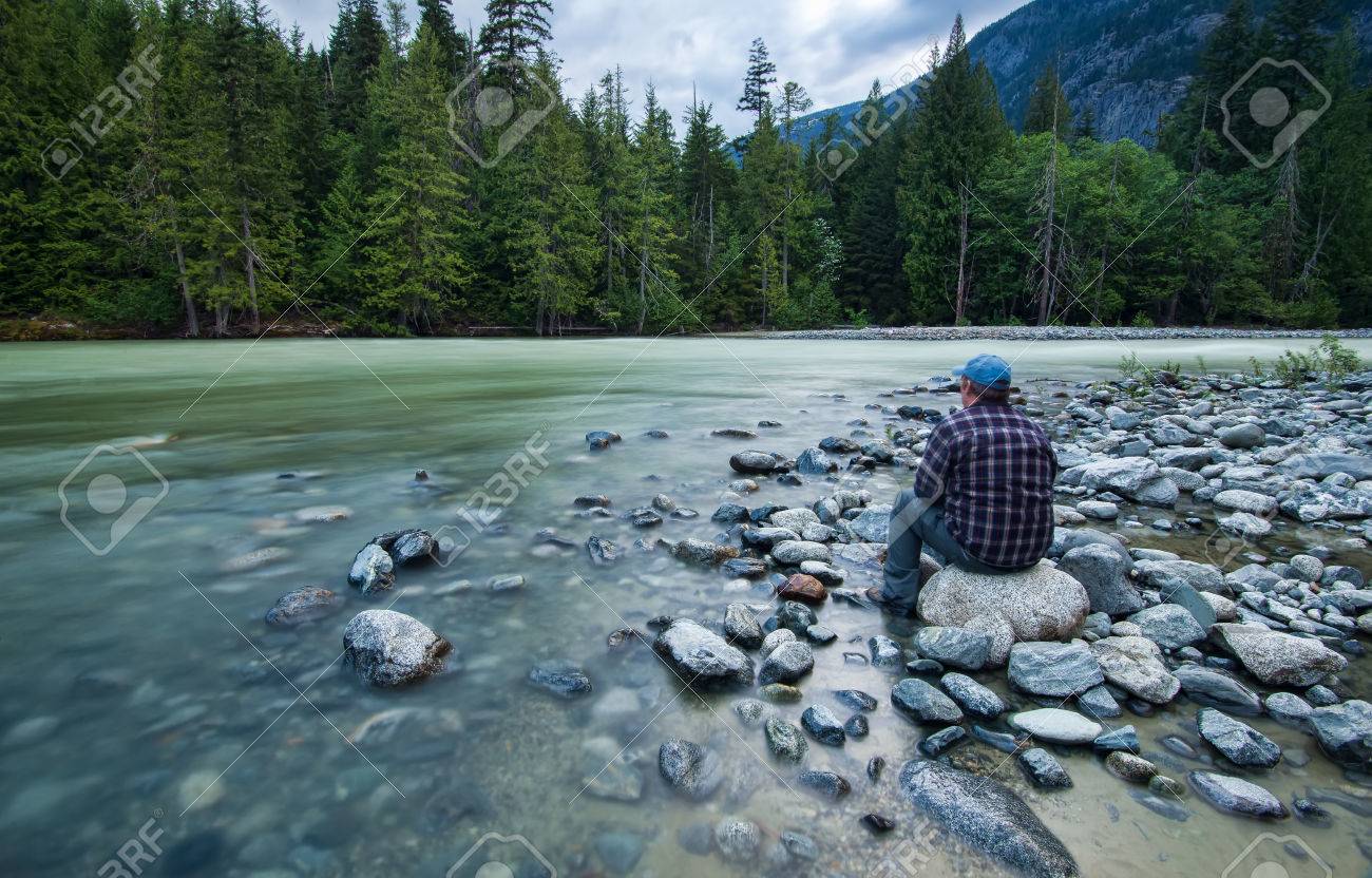 Paysage De Rivière Avec L'homme Assis Sur Un Rocher Banque D ...