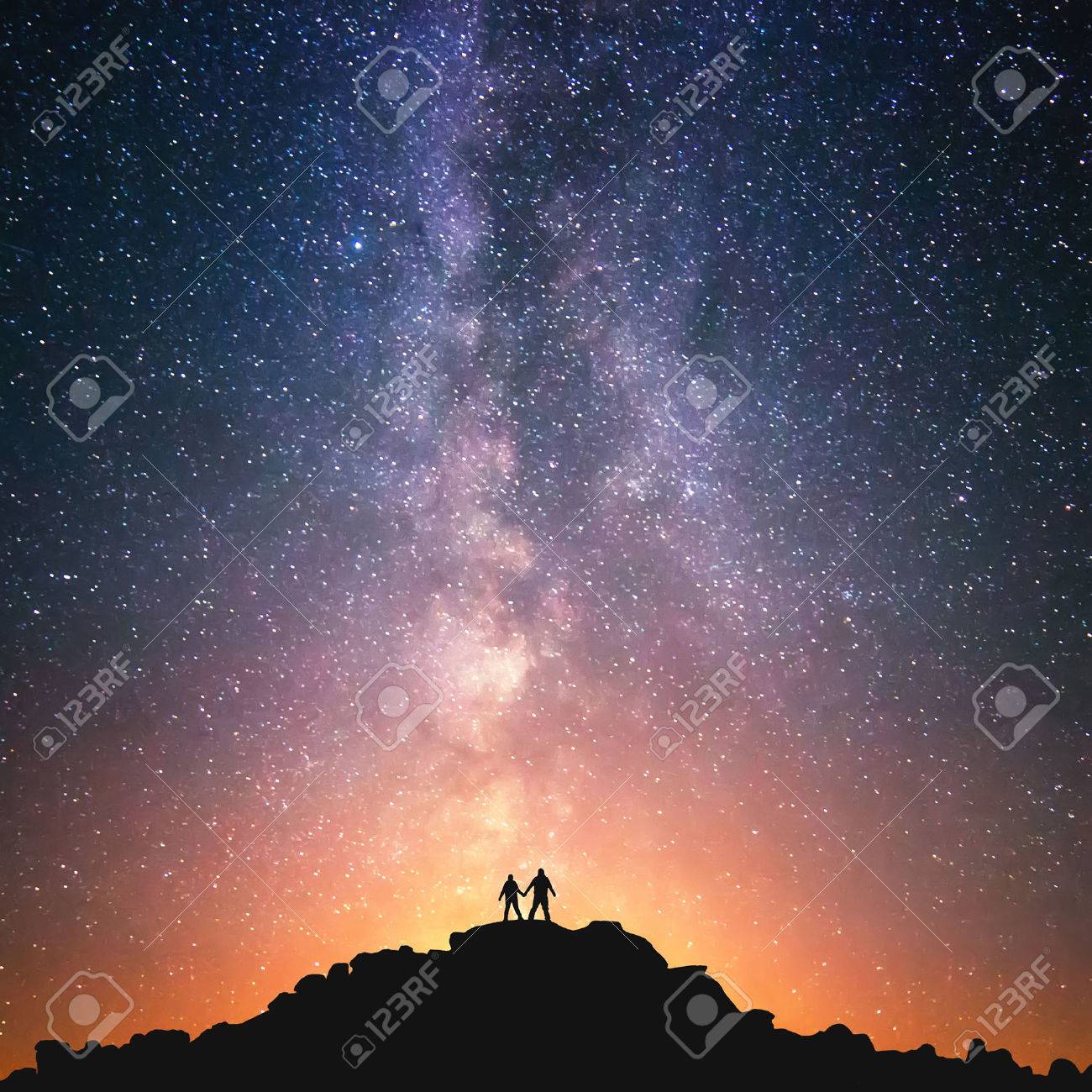 Silhouttes of two people standing together holding hands against the Milky Way on the top of the hill. - 48581910 Silhouttes of two people standing together holding hands against the Milky Way on the top of the hill. - 48581910