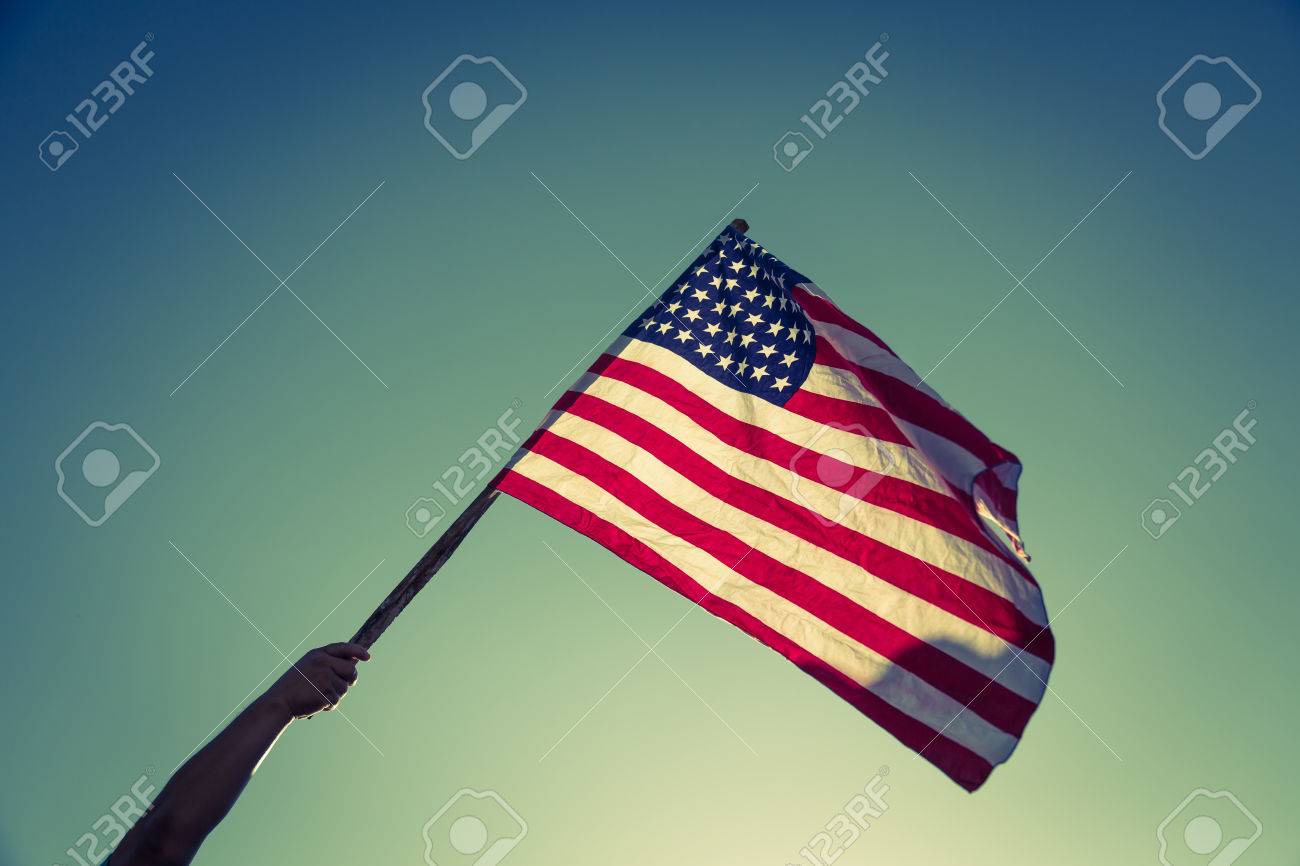 American flag with stars and stripes hold with hands against blue sky ( Filtered image processed vintage effect. ) - 42456723 American flag with stars and stripes hold with hands against blue sky ( Filtered image processed vintage effect. ) - 42456723
