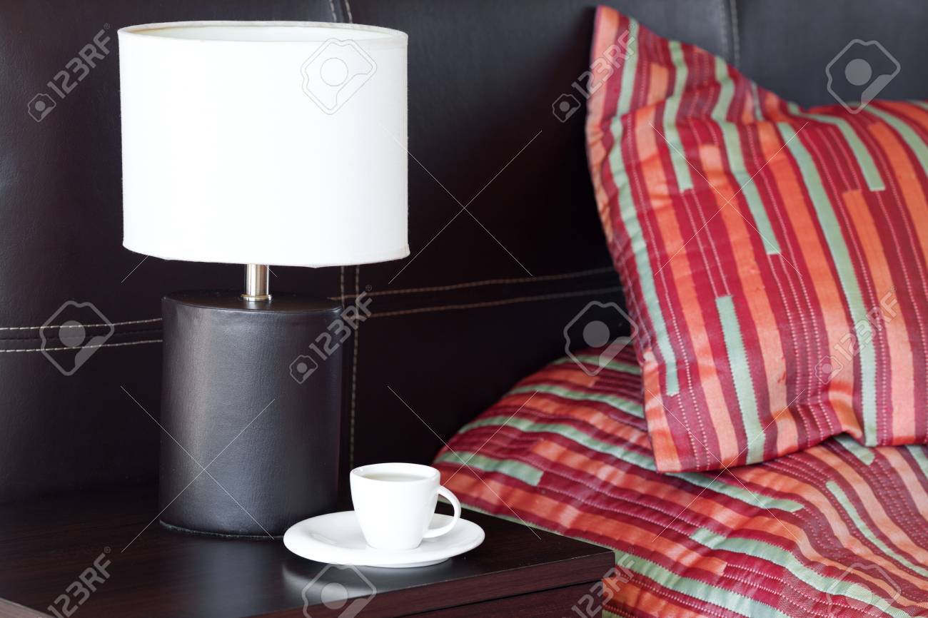 Bed With A Pillow A Cup Of Tea On The Bedside Table And Lamp