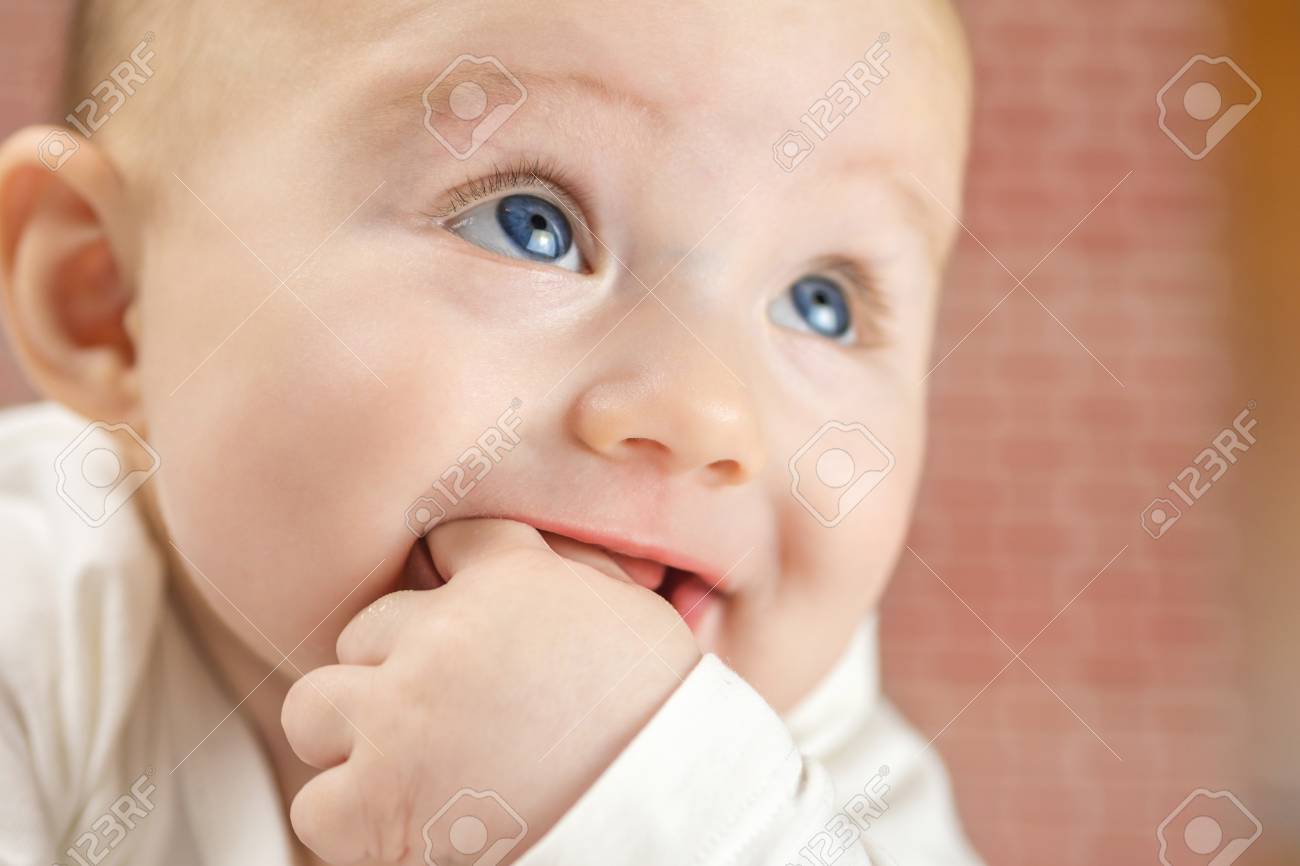 Gros Plan De Beau Bebe Heureux Mordre Sur Ses Doigts Aux Yeux Bleus Sur Fond Rouge Brique Banque D Images Et Photos Libres De Droits Image