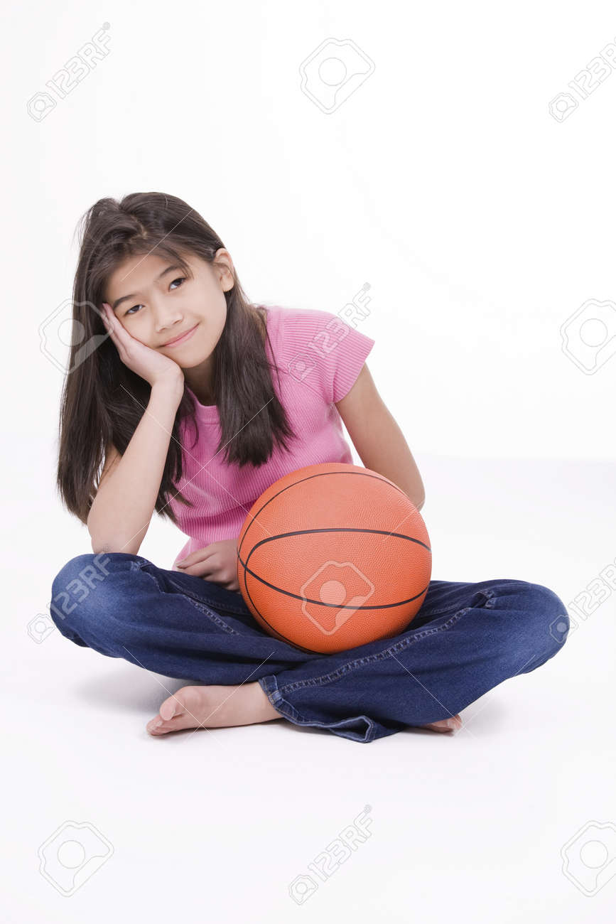 ten year old asian girl sitting on floor holding basketball stock