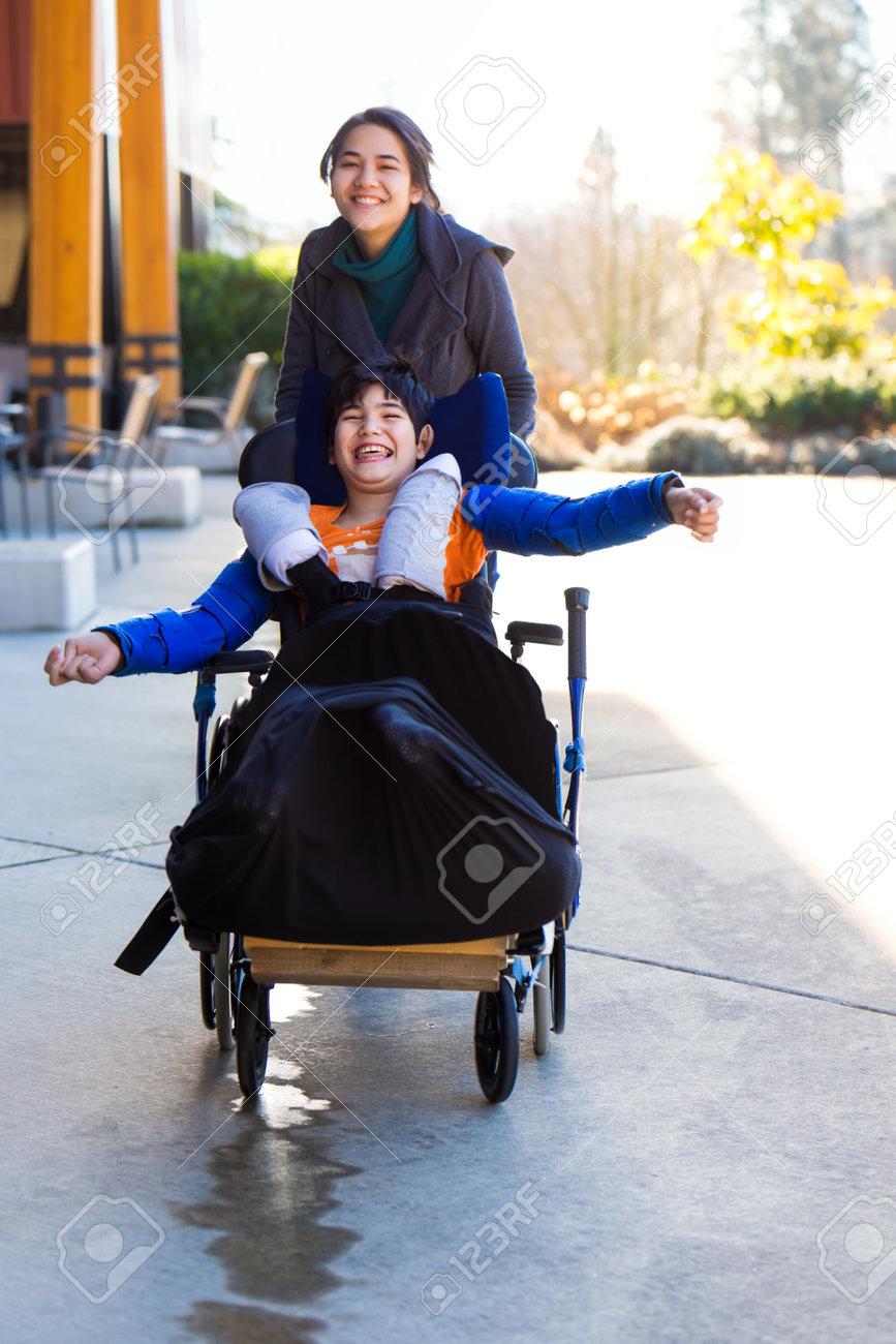 介護者は車椅子で若い障害のある少年を押し 外で一緒に走る の写真素材 画像素材 Image