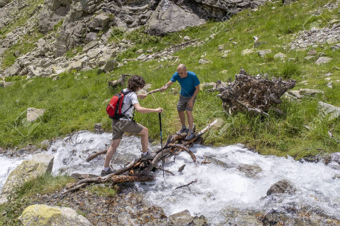 Man Helping A Woman To Cross A Mountain River In The Pyrenees.. Stock Photo, Picture And Royalty Free Image. Image 151089101.