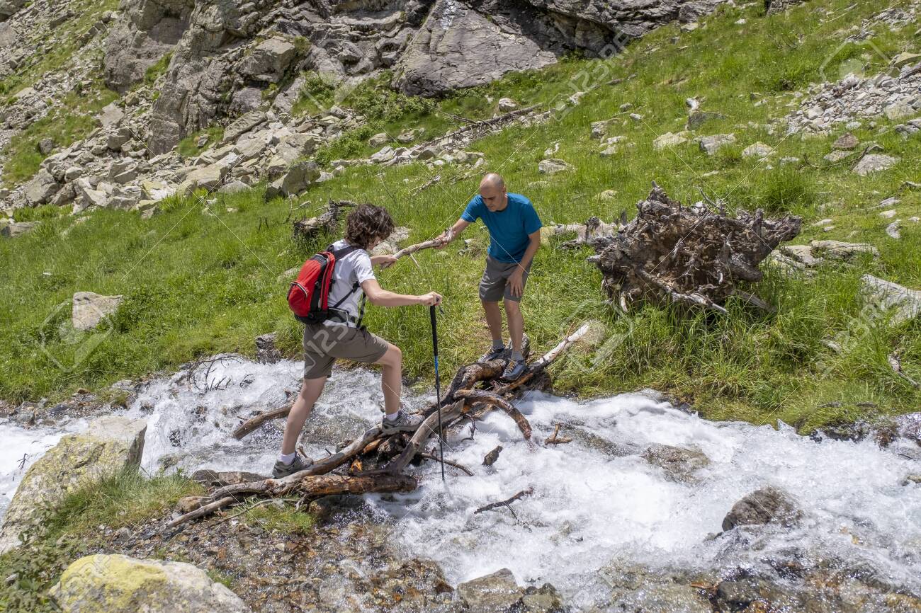 Man Helping A Woman To Cross A Mountain River In The Pyrenees.. Stock  Photo, Picture And Royalty Free Image. Image 151089101.