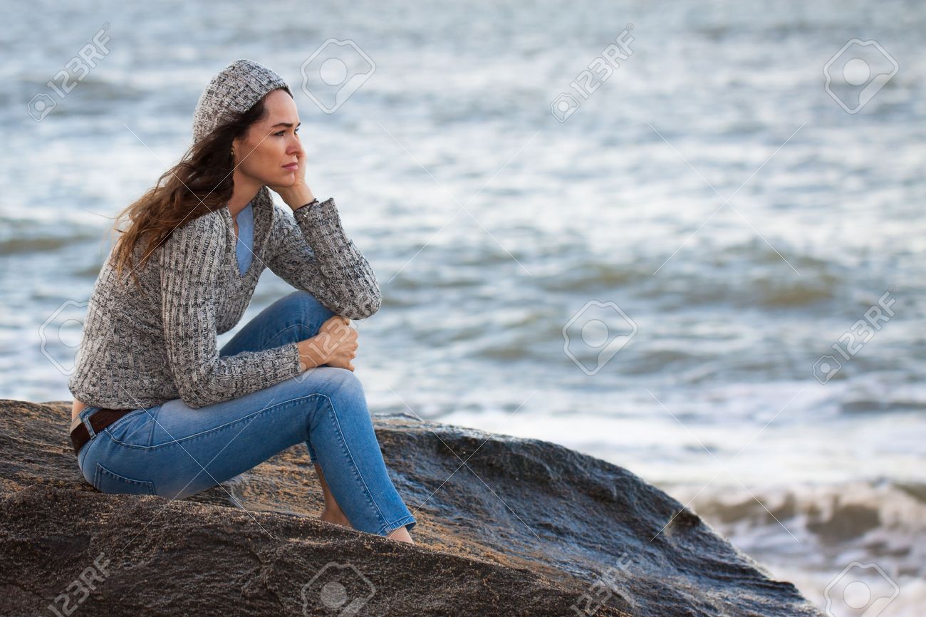 Sad And Thoughtful Woman Sitting By The Water Deep In Thought ...