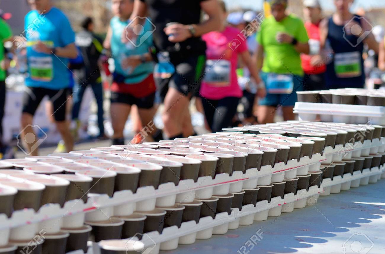 Marathon running race runners on road volunteer giving water and isotonic drinks on refreshment point - 39696587 Marathon running race runners on road volunteer giving water and isotonic drinks on refreshment point - 39696587