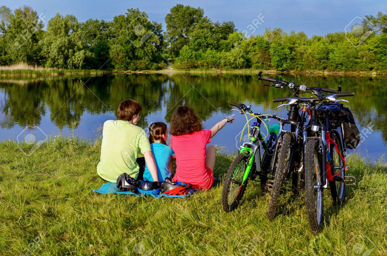 Family bike ride outdoors, active parents and kid cycling and relaxing near beautiful river - 42906784 Family bike ride outdoors, active parents and kid cycling and relaxing near beautiful river - 42906784