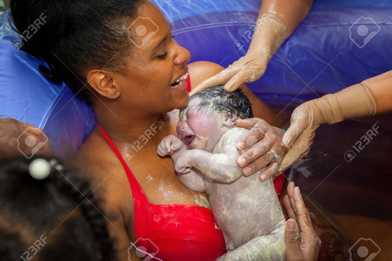 Une Mere Americaine Africaine Heureux Holding Sa Toute Nouvelle Petite Fille Apres Sa Prestation Dans Une Piscine D Accouchement A La Maison Le Bebe Est Couvert De Vernix Et La Maman Se Moque