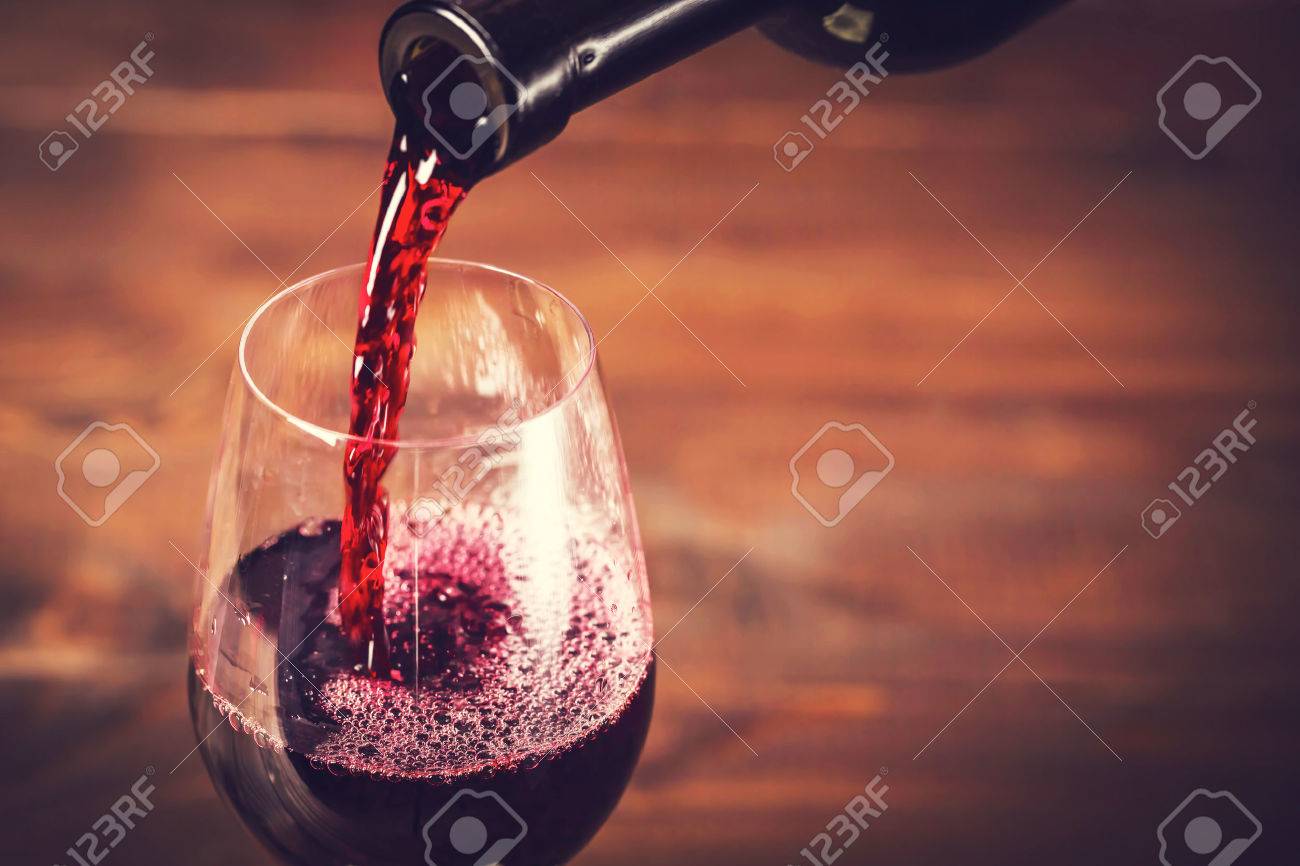 Pouring red wine into the glass against wooden background - 51975832 Pouring red wine into the glass against wooden background - 51975832