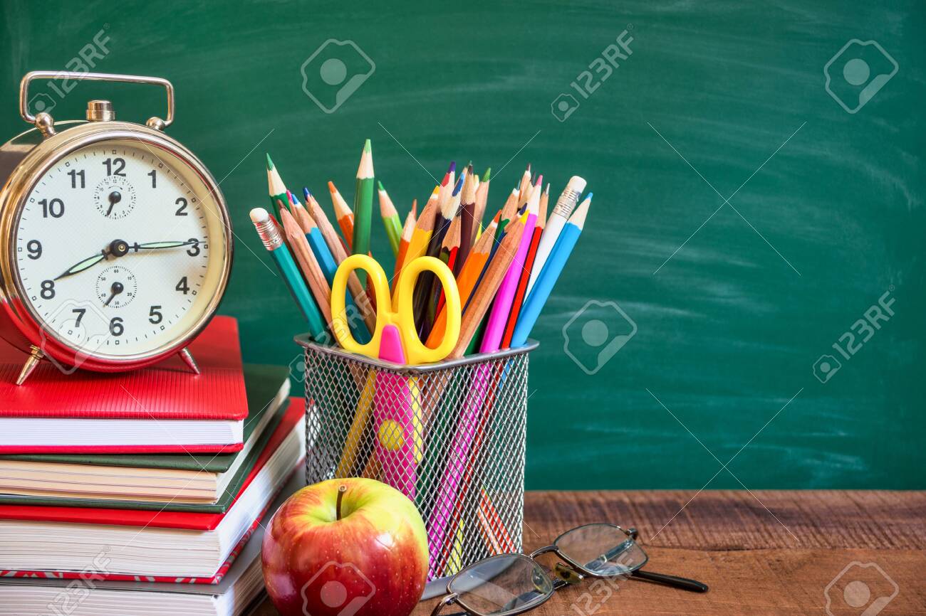 School supplies, alarm clock, apple and books on wooden table in front of the school chalkboard. Back to school concept. - 131839326 School supplies, alarm clock, apple and books on wooden table in front of the school chalkboard. Back to school concept. - 131839326