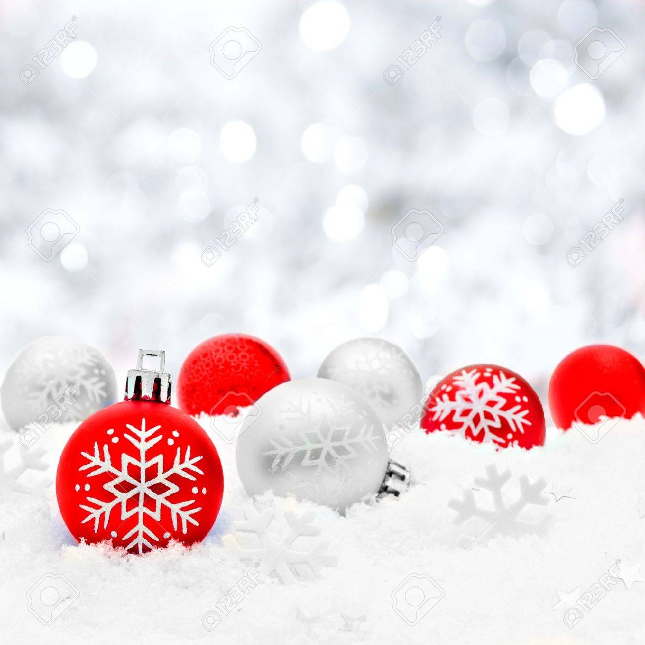 Red and silver Christmas baubles in snow with twinkling silver background - 33246633
