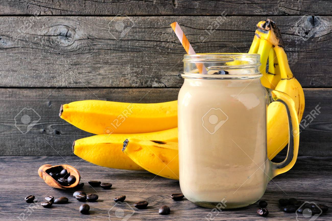 コーヒー バナナスムージー コーヒー豆とバナナを背景にしたメイソンジャー 素朴な木の背景に対するサイドビュー の写真素材 画像素材 Image