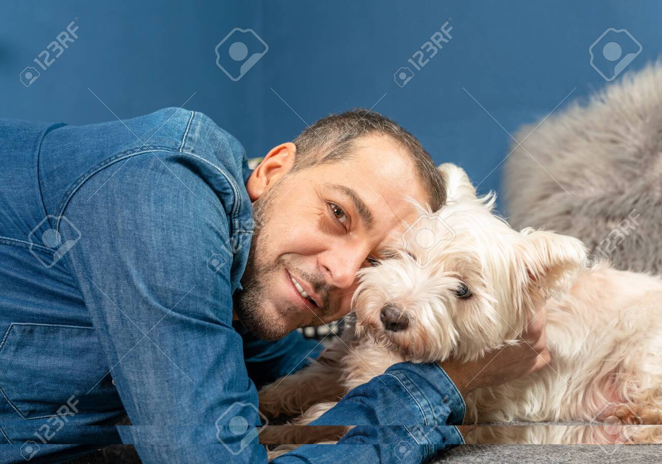 A man cuddles with his dog on the couch - 143720543 A man cuddles with his dog on the couch - 143720543