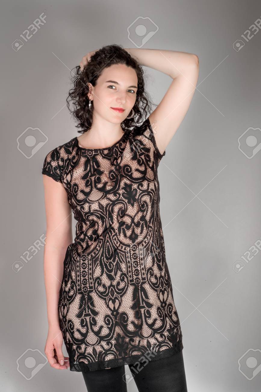 Tre Quarti Ritratto Di Una Giovane Donna Nella Sua Metà Degli Anni Venti Con I Capelli Neri E Indossa Un Abito Nero Su Sfondo Grigio