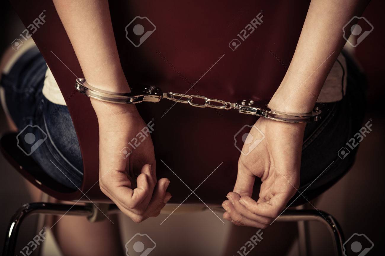 若い男の子の椅子の後ろに手錠に手錠をはめられた手のビューを閉じると警察によって尋問される囚人を開催 の写真素材 画像素材 Image