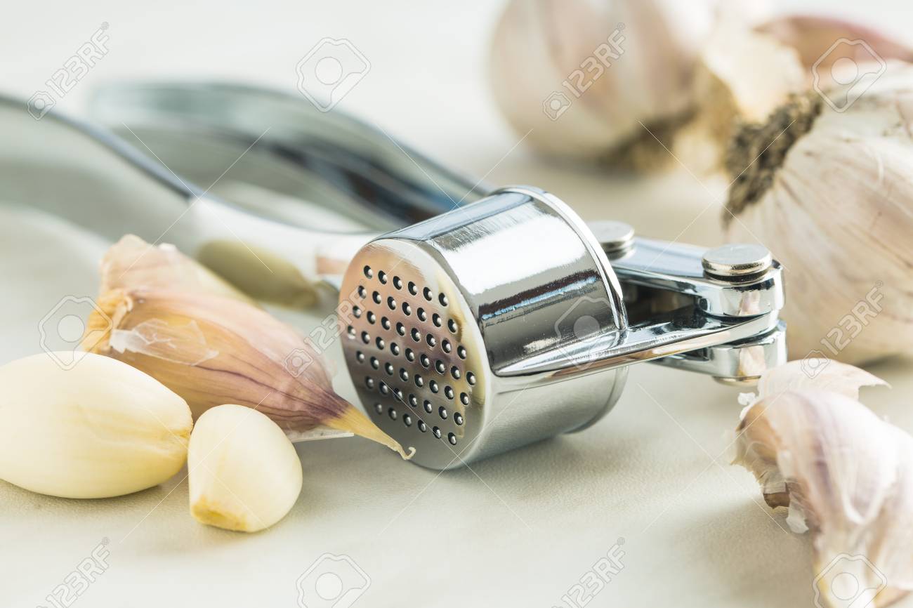 Garlic And Garlic Press On Kitchen Table Stock Photo Picture And