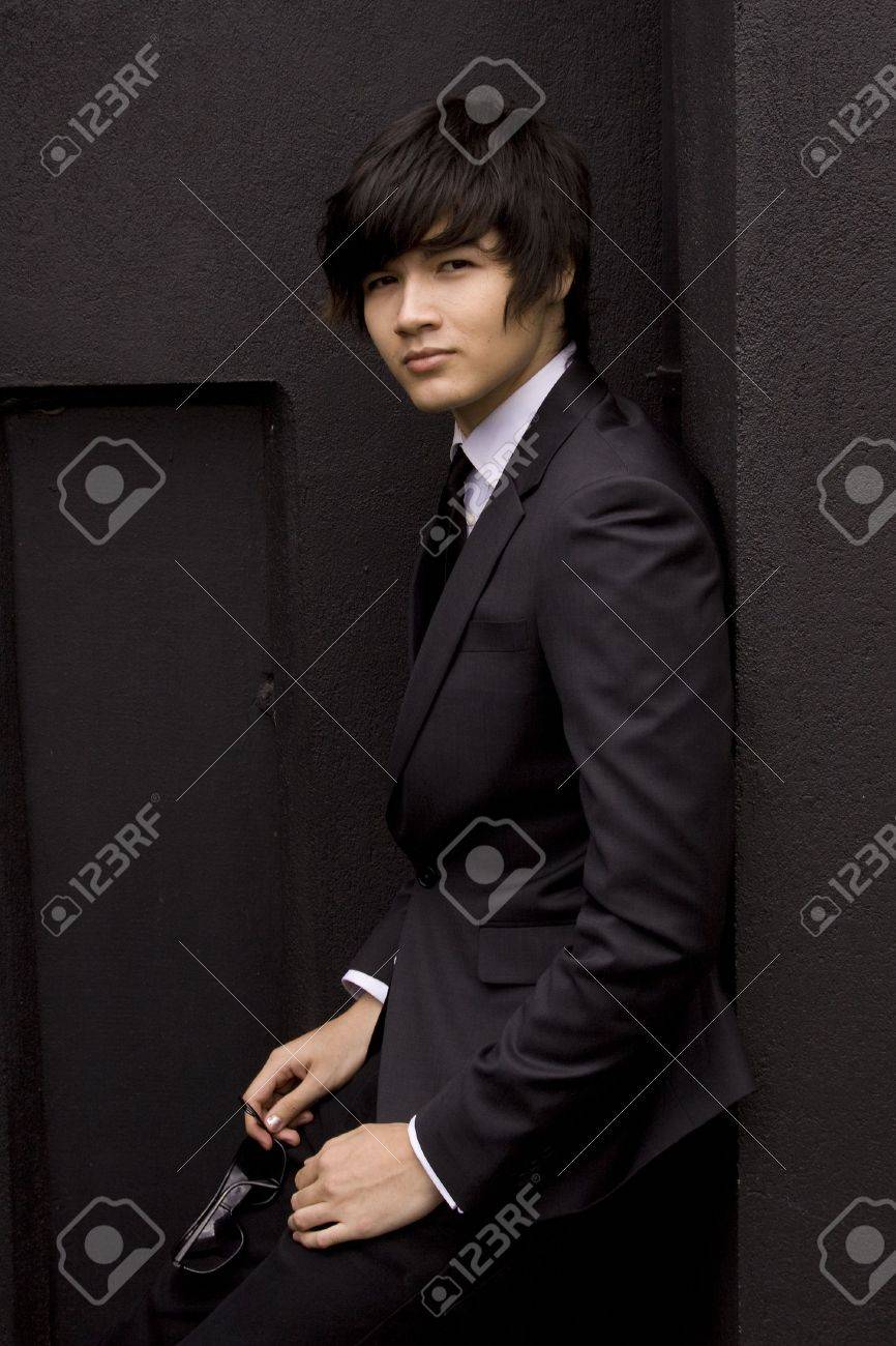 Young model in a black suit against a black wall - 6056470 Young model in a black suit against a black wall - 6056470