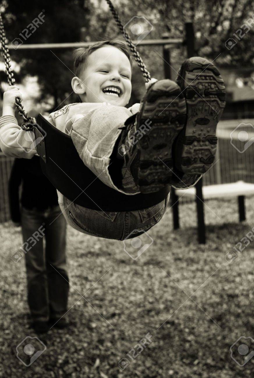 A little boy having a great time on a swing in a playground - 7873684 A little boy having a great time on a swing in a playground - 7873684