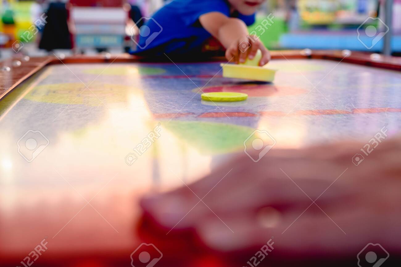 Hand Holding A Stick To Hit Disc In The Table Air Hockey Game
