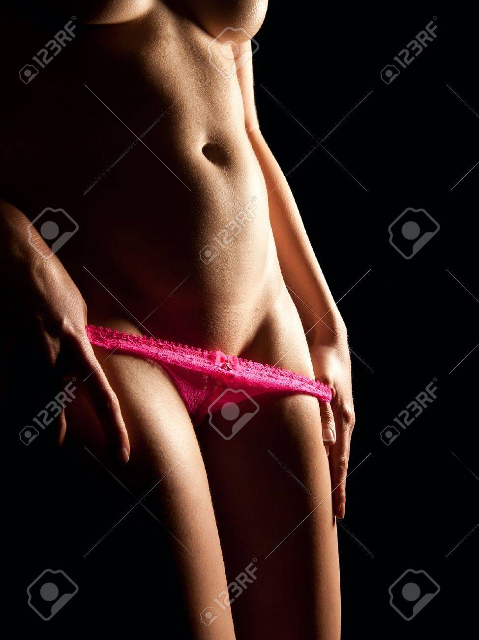 Sexy Young Woman Taking Off Beautiful Pink Panties In Front Of Black Background Stock Photo, Picture And Royalty Free Image