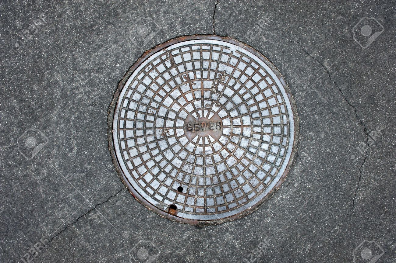 An old sewer manhole coversurrounded by an asphalt street - 10487851 An old sewer manhole coversurrounded by an asphalt street - 10487851