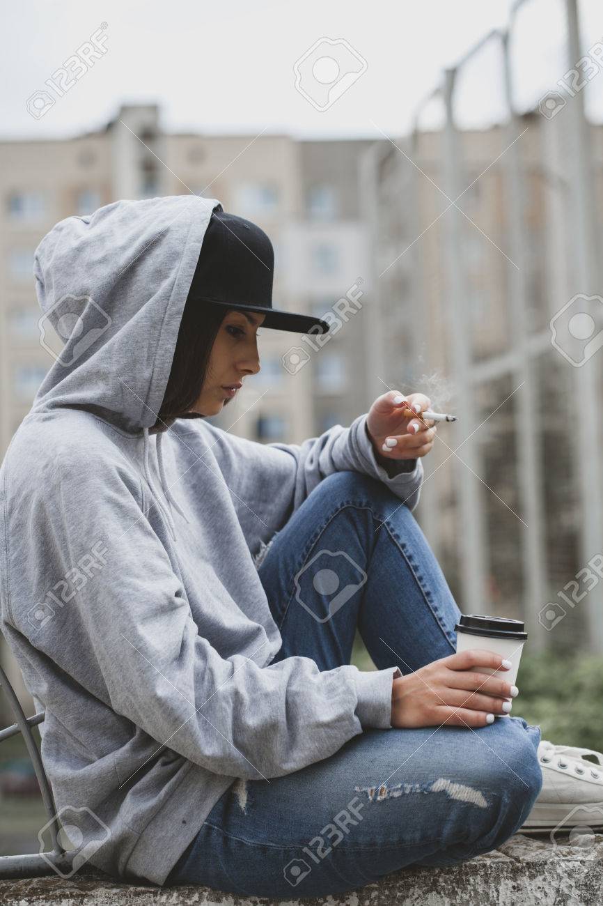 アウトドア ライフ スタイル肖像画 Os 若い女性の広場で地面に座って タバコを吸って 紙コップからコーヒーを飲みます パーカー キャップ ジーンズ スニッカーズ垂らす少女コンセプト の写真素材 画像素材 Image アウトドア ライフ スタイル肖像画 Os 若い女性の広場で地面に座って タバコを吸って 紙コップからコーヒーを飲みます パーカー キャップ ジーンズ スニッカーズ垂らす少女コンセプト の写真素材 画像素材 Image