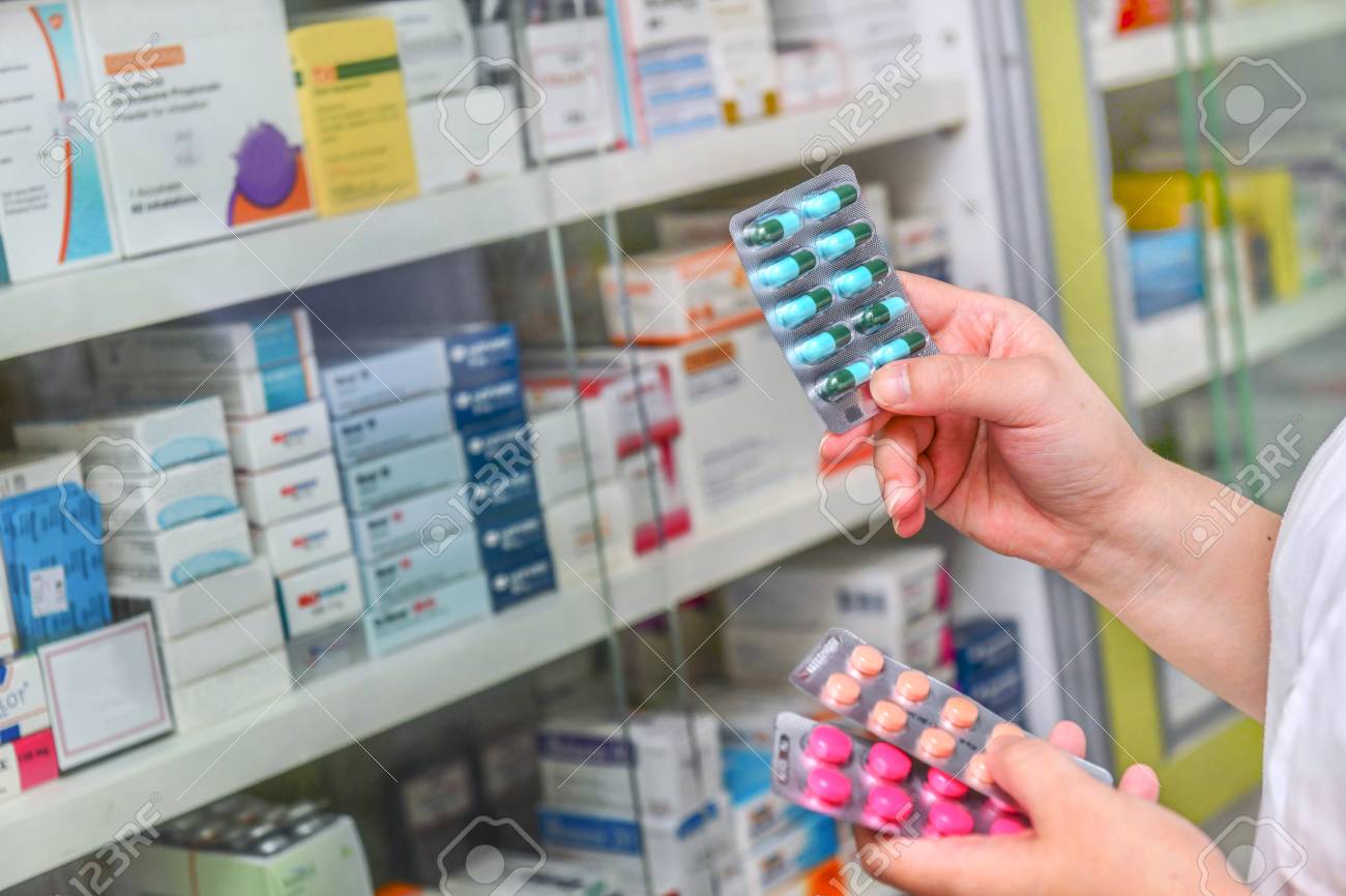 Pharmacist holding medicine box and capsule pack in pharmacy drugstore. - 100324769 Pharmacist holding medicine box and capsule pack in pharmacy drugstore. - 100324769