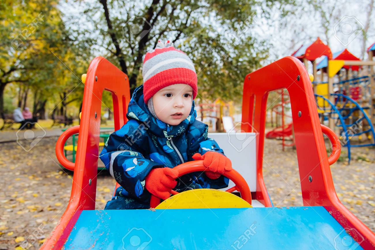 子供は遊び場で子供の車の車輪に座っている の写真素材 画像素材 Image
