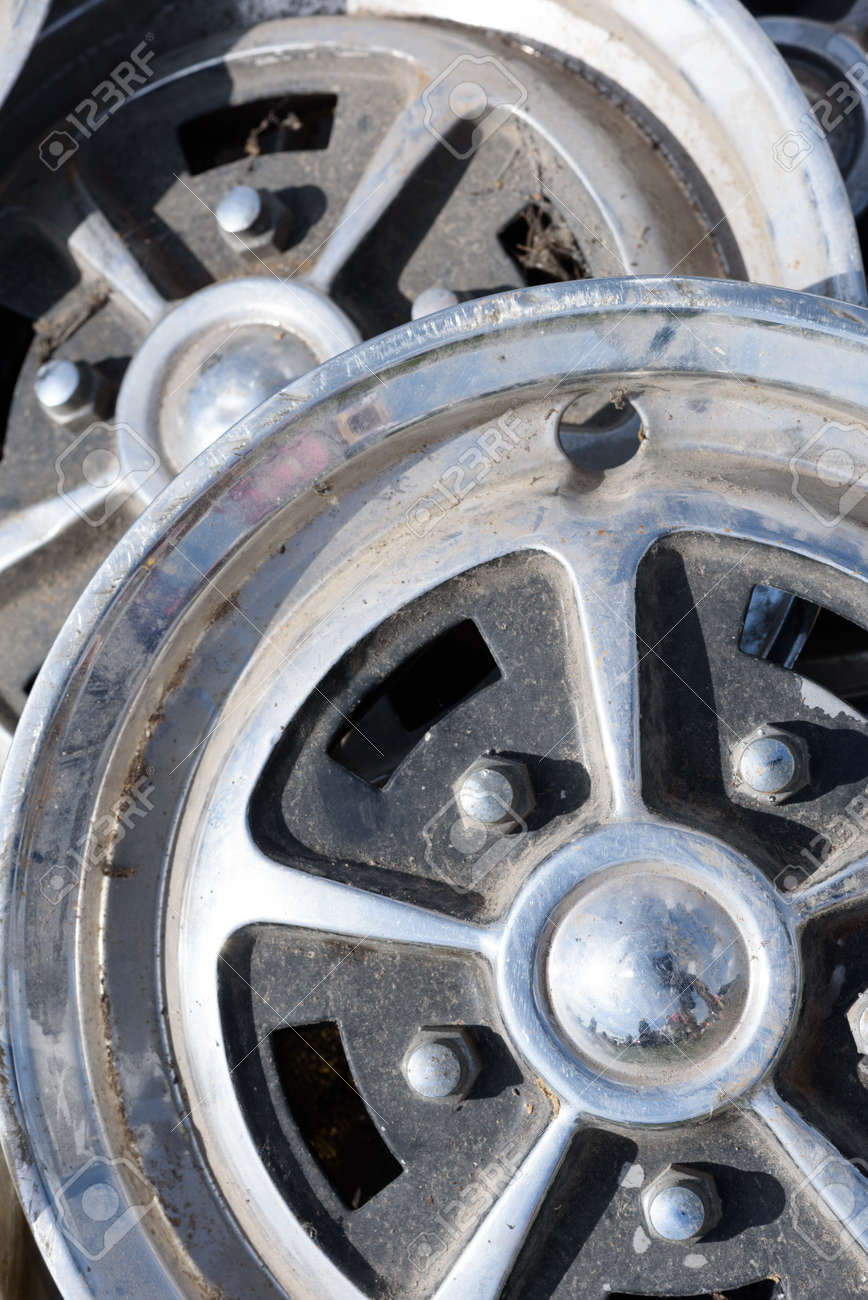 Closeup of tow car wheel trims in alloy metal silver with dirt and grime showing their used condition - 155300736 Closeup of tow car wheel trims in alloy metal silver with dirt and grime showing their used condition - 155300736