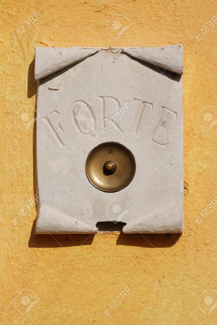 A Door Bell On A Yellow Wall With The Word Forte Meaning Strong