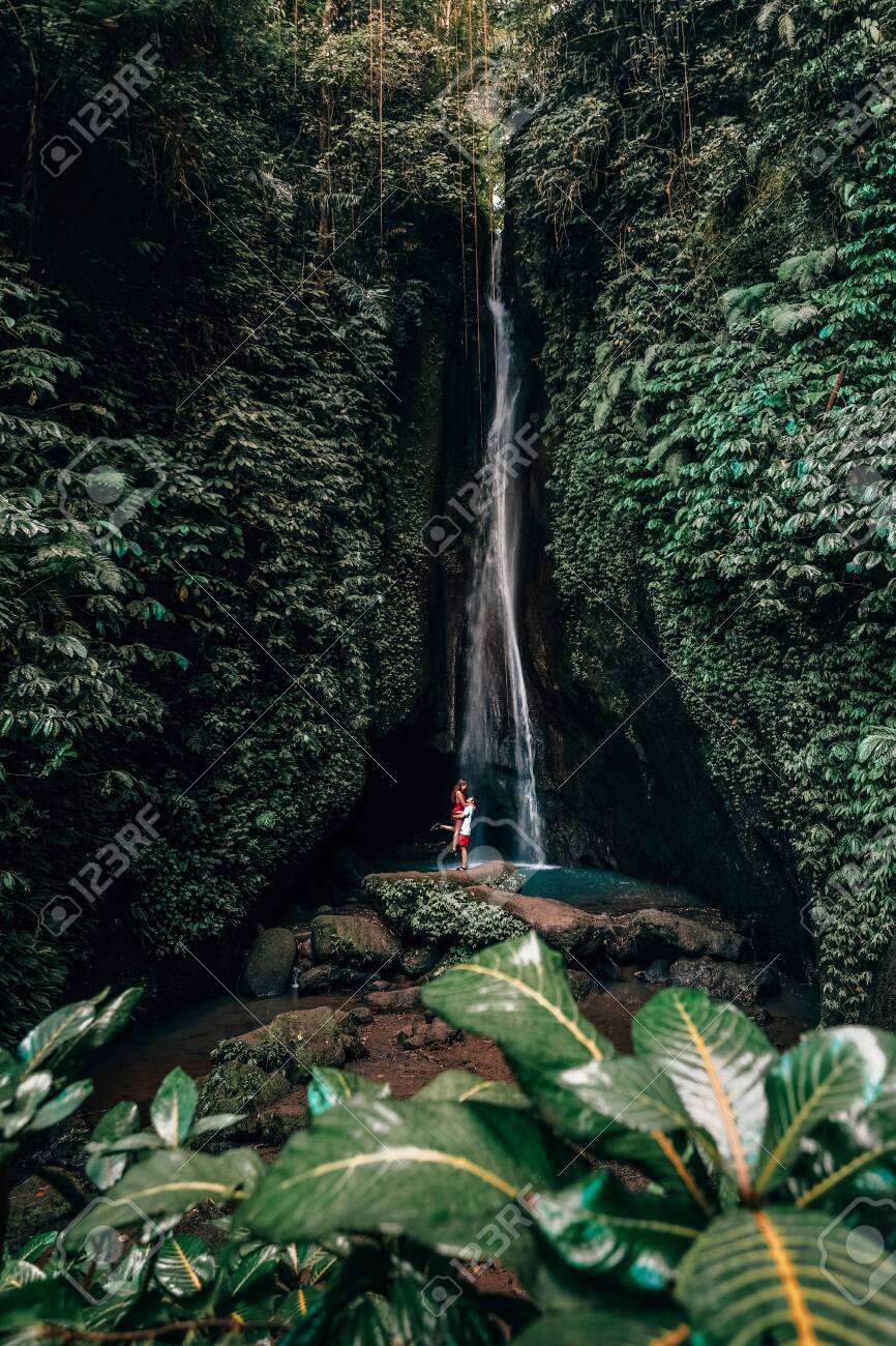 Traveling young couple with tropical rainforest in Bali enjoying life at beautiful Lake Lake waterfall. - 132748715 Traveling young couple with tropical rainforest in Bali enjoying life at beautiful Lake Lake waterfall. - 132748715