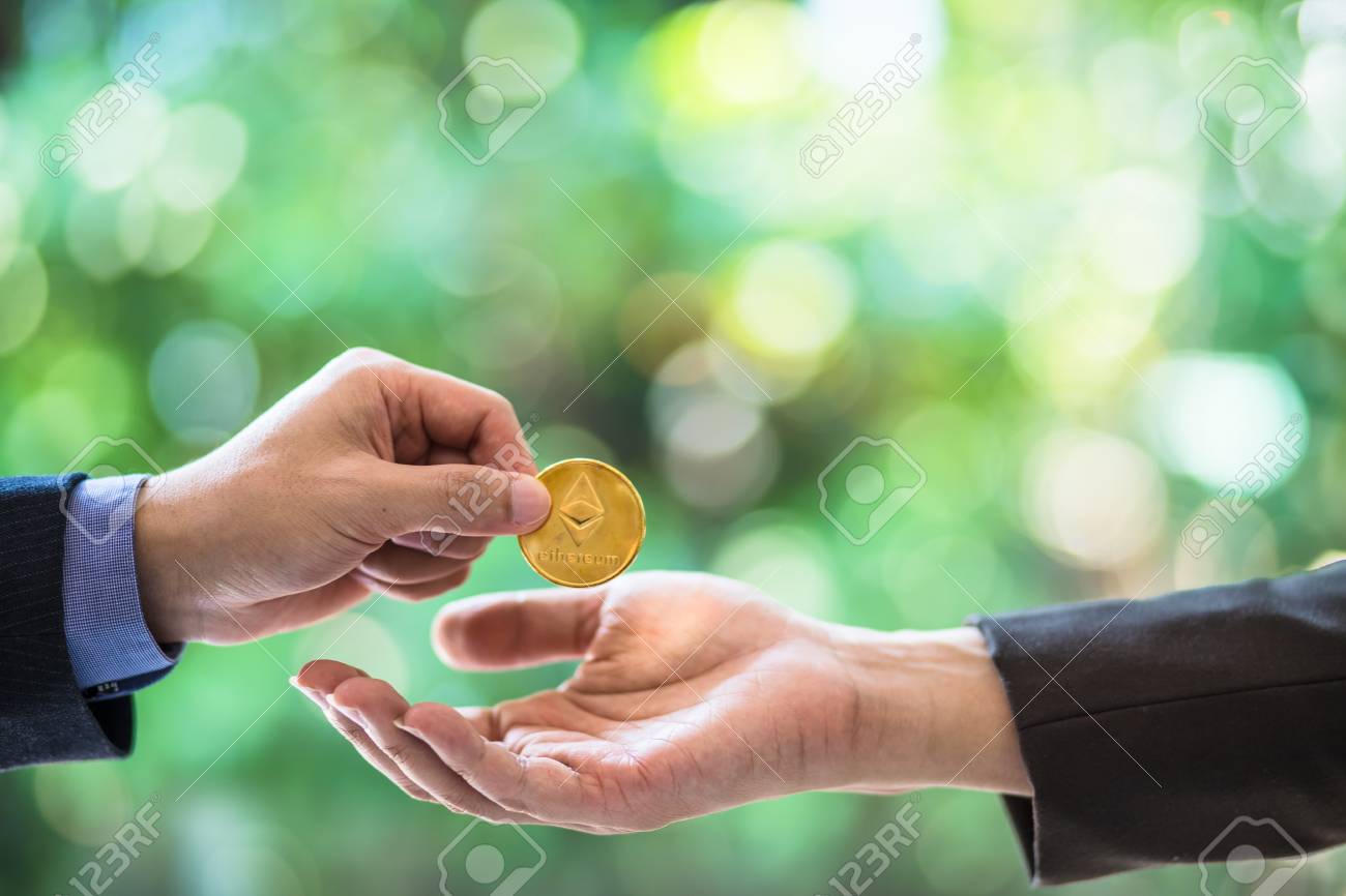 두 사업가의 흐릿한 손은 이더 리움의 동전을 거래하고 있습니다. 이더 리움의 상징 동전. 전자 화폐 교환, 비즈니스, 디지털 통화,  금융 및 기술 개념. 정원 Bokeh 배경입니다. 로열티 무료 사진, 그림, 이미지 그리고