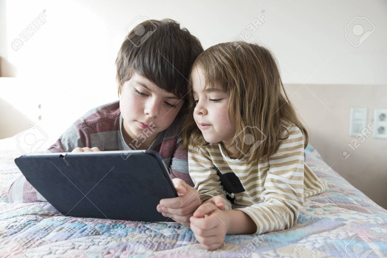 Children playing with a digital tablet on the bed - 37150051 Children playing with a digital tablet on the bed - 37150051