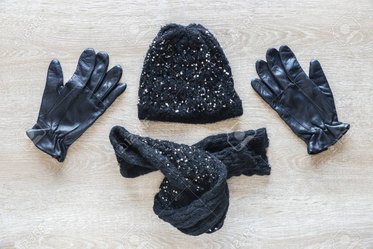 木の床に手袋 帽子 スカーフで作ったおしゃれな黒服のセット の写真