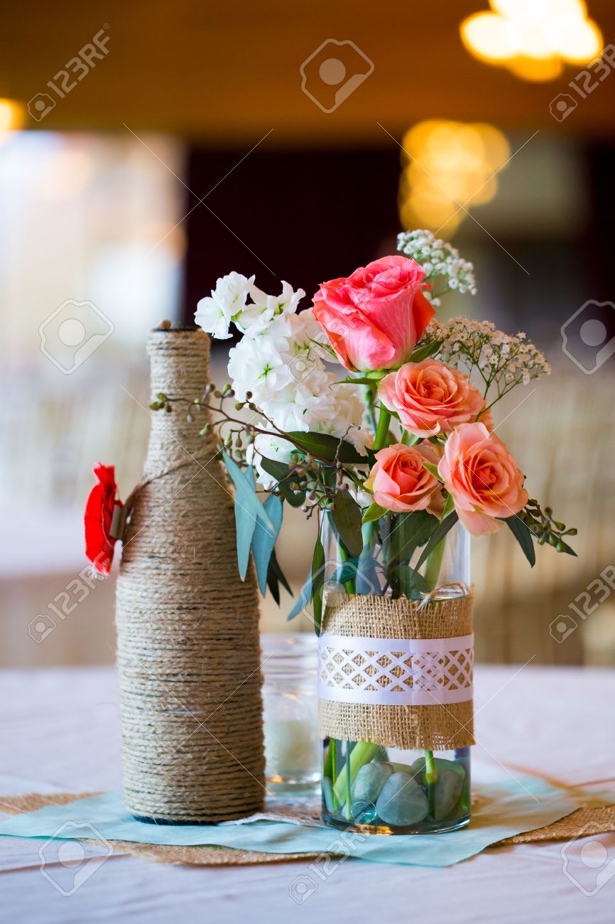 ワインのボトルと Diy の結婚式の装飾テーブル センター ピース黄麻布のひもにラップされ ばら色の花 の写真素材 画像素材 Image