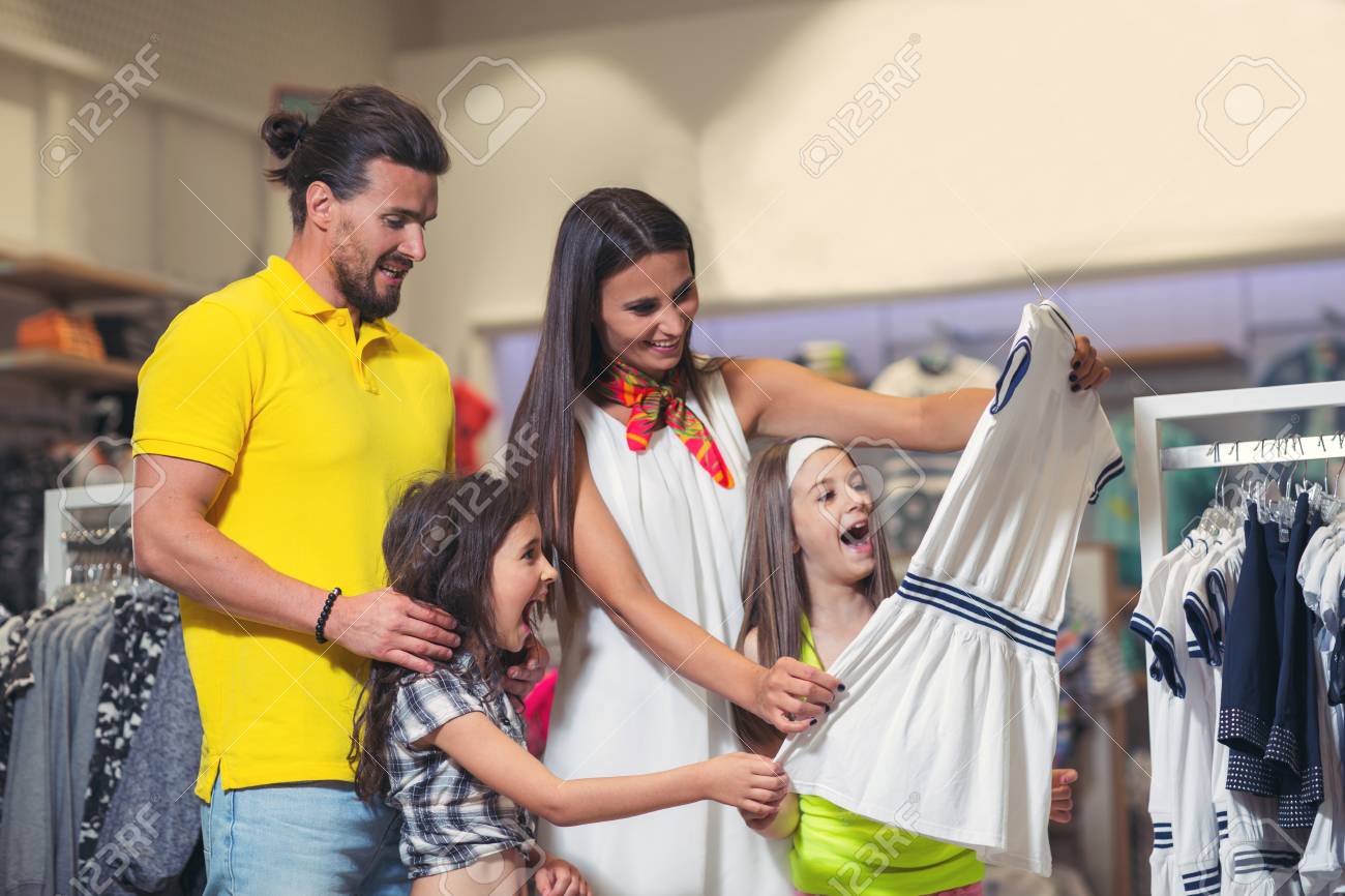 Chica Feliz Eligiendo Ropa. La Familia Está Comprando En Una De Niños. Fotos, Retratos, Imágenes Y Fotografía De Archivo Libres De Derecho. Image 85548673.