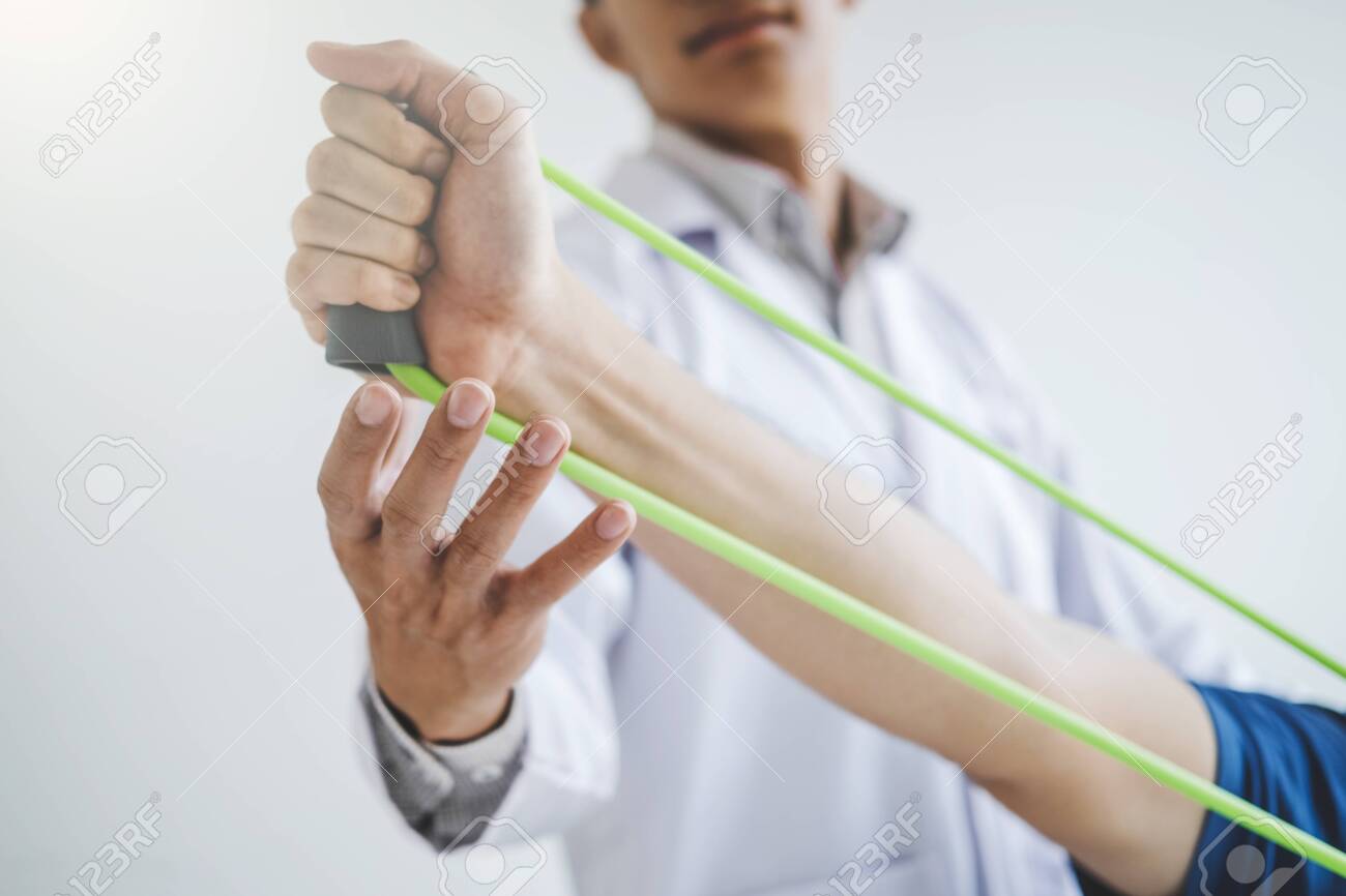 Physiotherapist man giving resistance band exercise treatment About Chest muscles and Shoulder of athlete male patient Physical therapy concept - 135491923 Physiotherapist man giving resistance band exercise treatment About Chest muscles and Shoulder of athlete male patient Physical therapy concept - 135491923